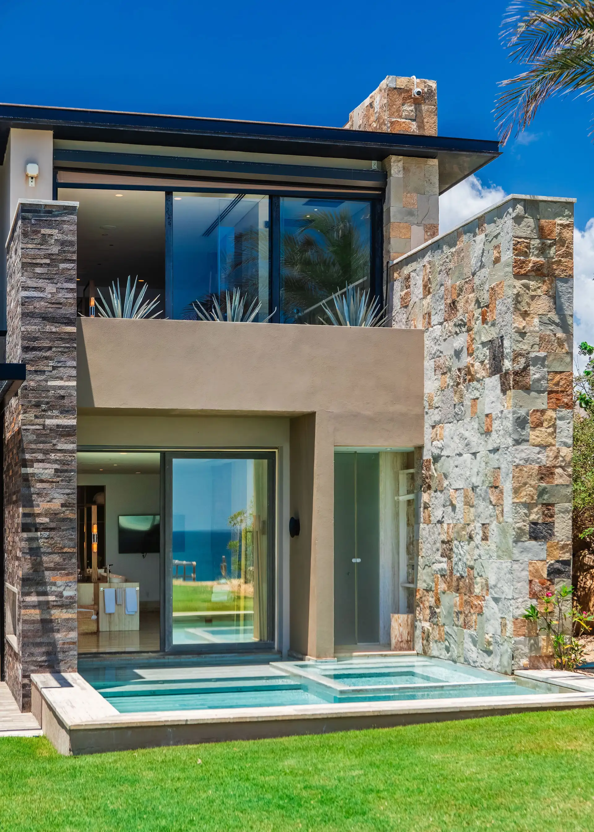 A private plunge pool and spa terrace off the primary suite, framed by natural stone walls, with the bathroom opening directly onto the pool deck.