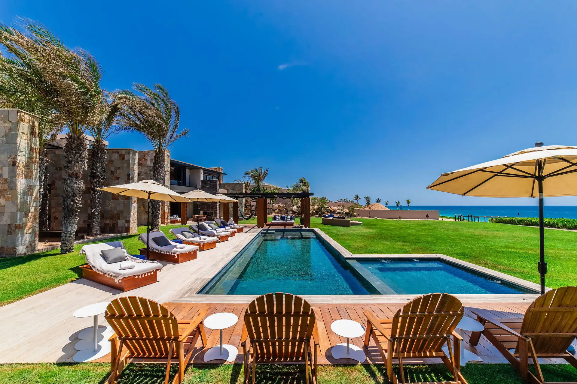 The private pool deck at the residence, with loungers arranged along the water's edge beneath open Baja sky.