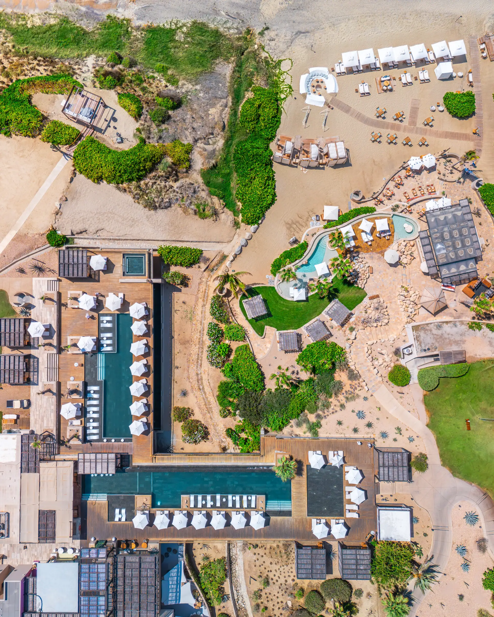 Aerial top-down view of the resort's pool complex and beach club, framed by dunes.