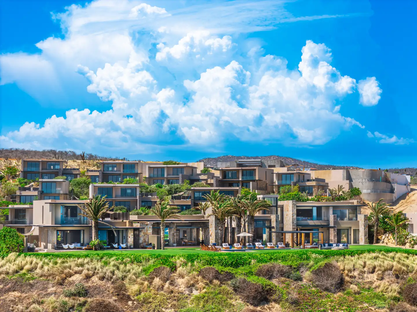 Aerial view of the Grand Reserve residences at Zadún, dramatic cloud cover overhead, coastline and hillside terrain beyond.