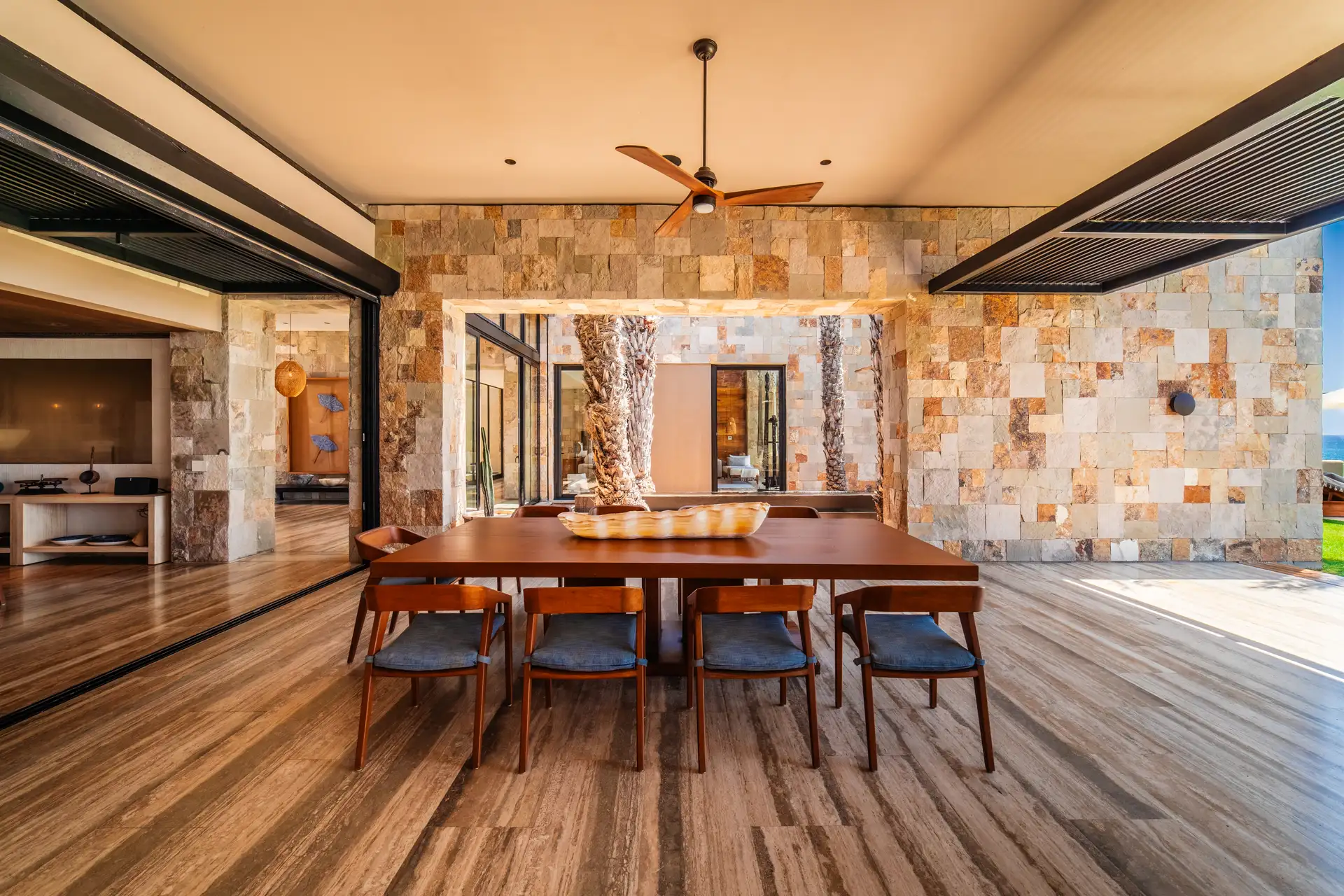 Open-air dining pavilion with a stone accent wall, overlooking the lawn.