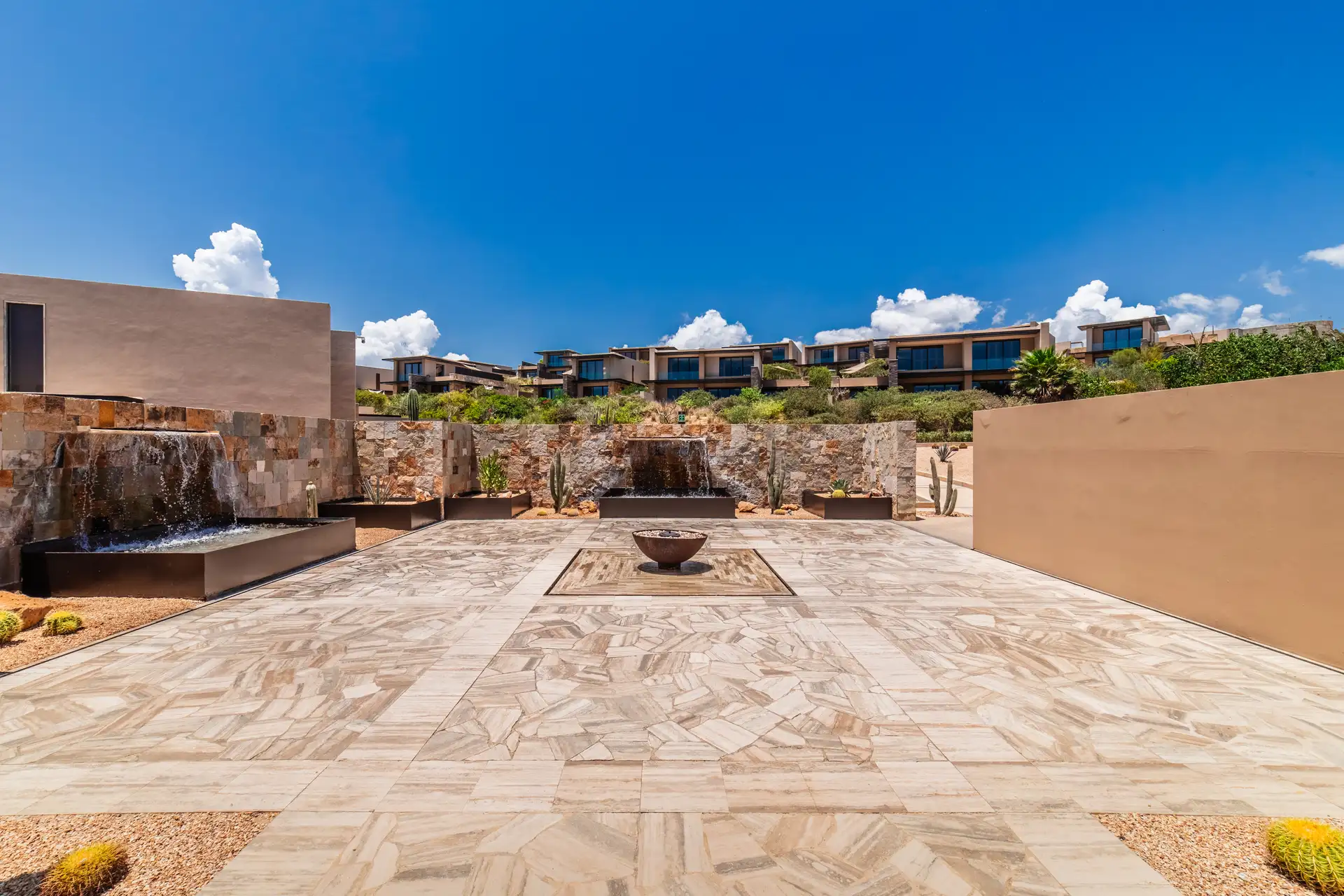 Courtyard fire pit terrace with a stone water feature and ocean view.