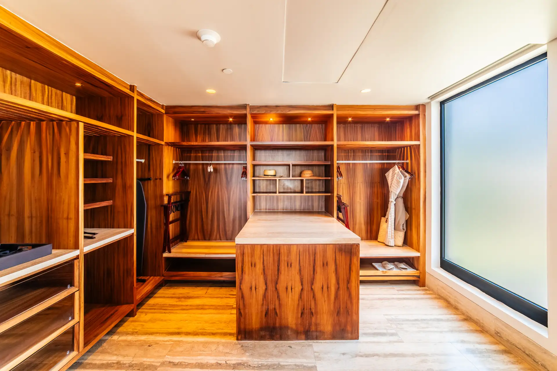 Walk-in closet with custom wood built-ins, open shelving, and a central dressing island.