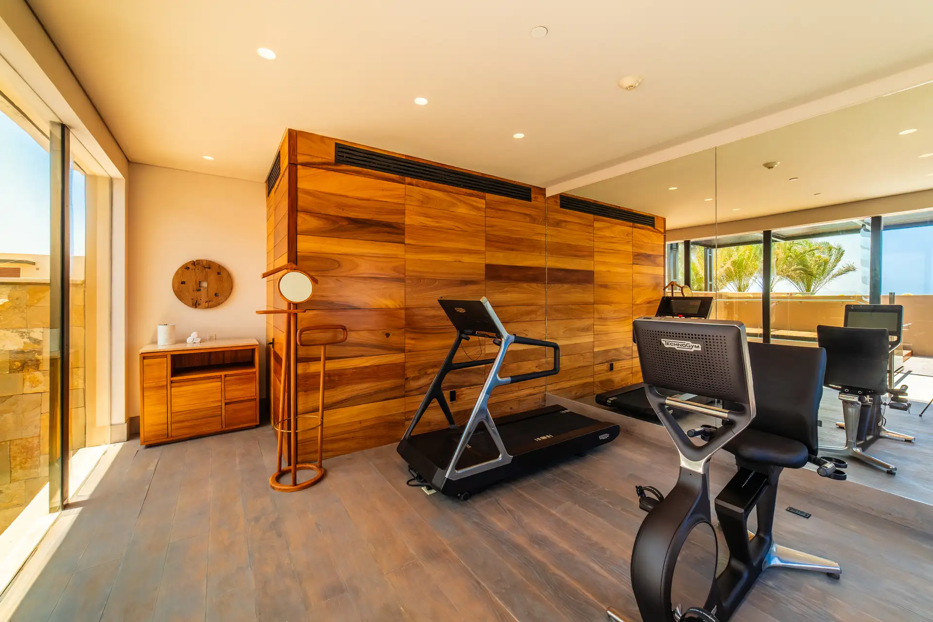 Private residence gym with treadmills and free weights, wood-paneled walls.